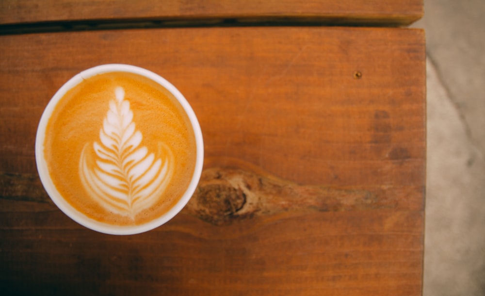 cappuccino in white ceramic mug on brown wooden table