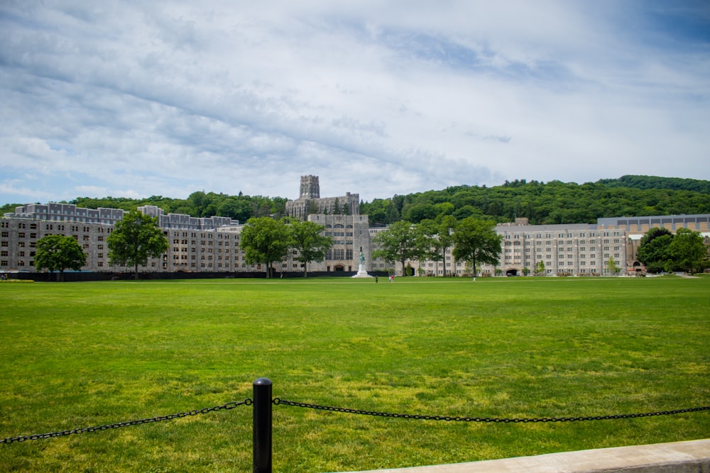 green grass field near city buildings under white cloudy sky during daytime