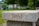 A stone bench with the word 'TRUST' engraved on its side is set in a lush, green park. The background features trees, blurred foliage, and a few indistinct people, creating a serene and calming atmosphere.