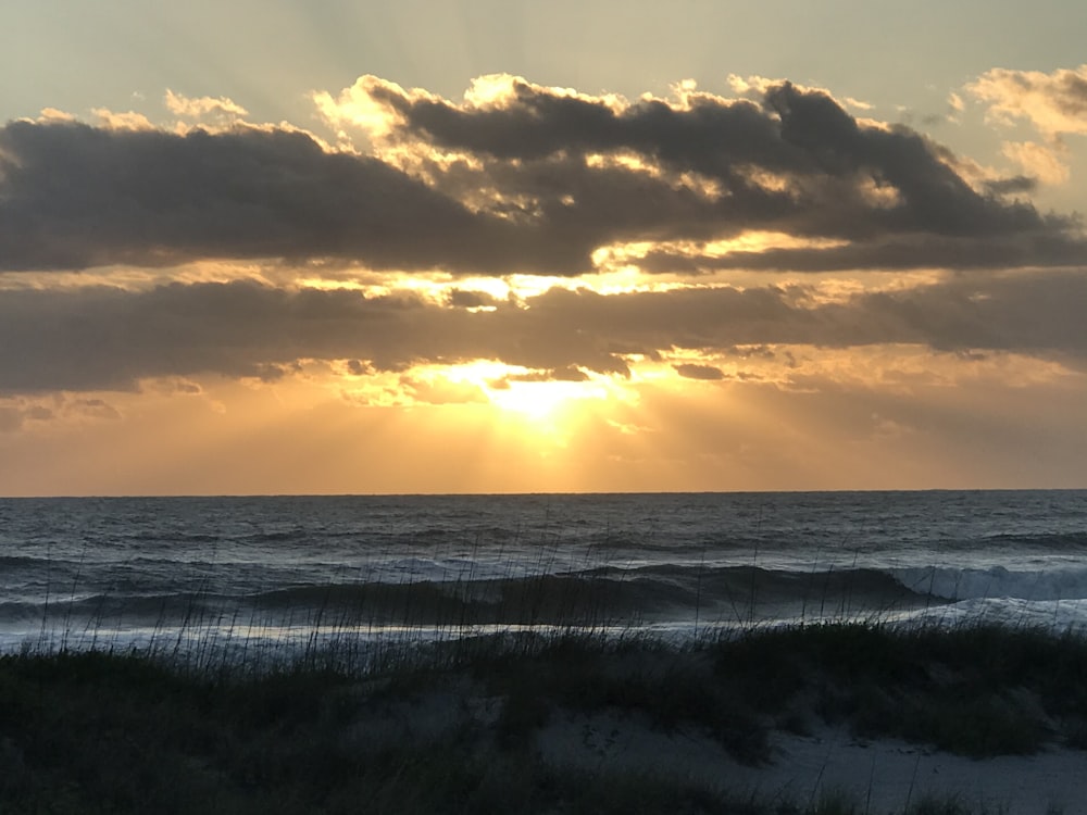 body of water under cloudy sky during sunset