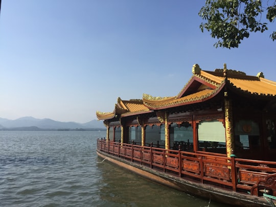 brown wooden house on body of water during daytime in Hangzhou China
