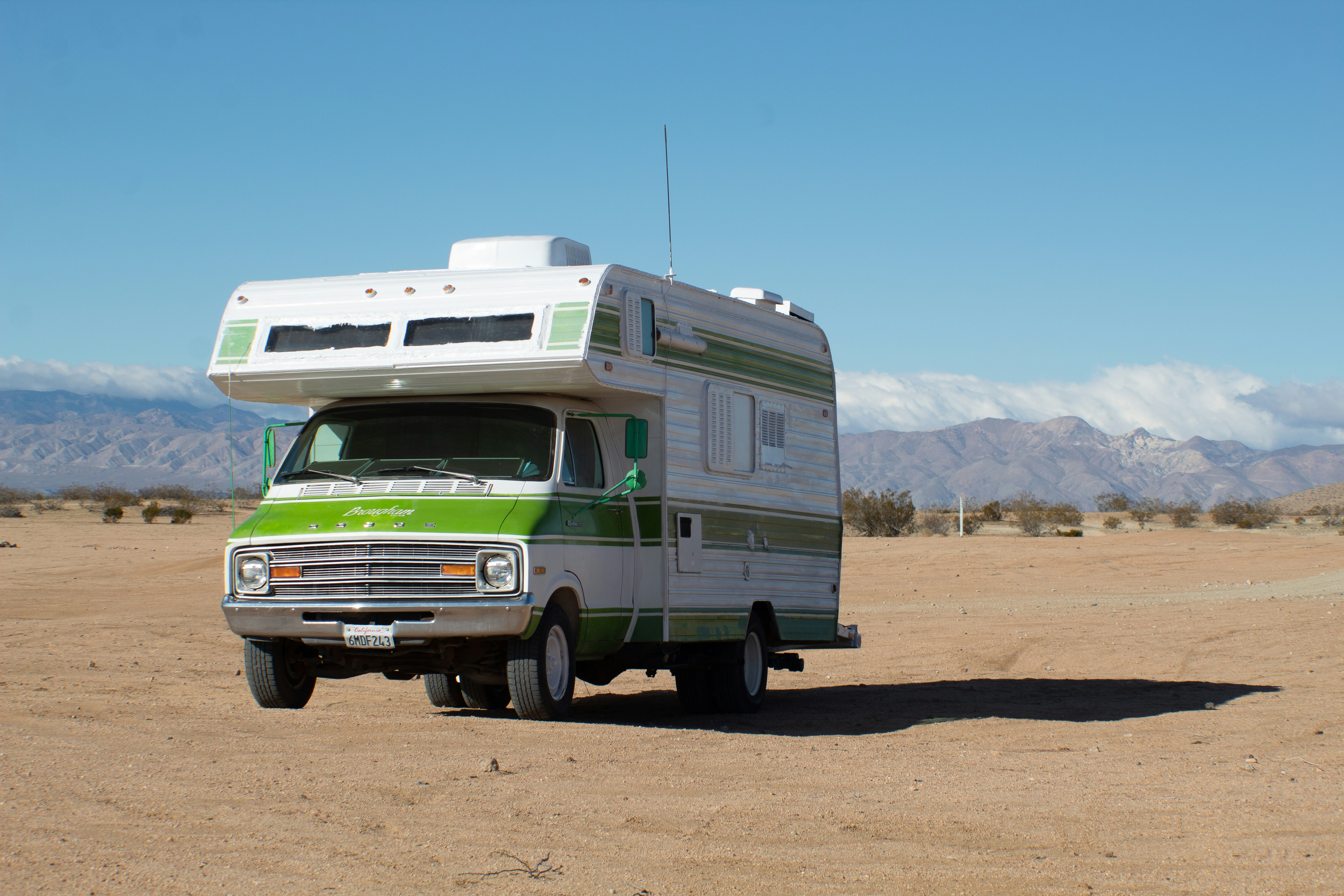white and green rv on brown field under blue sky during daytime