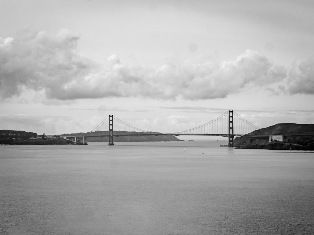 grayscale photo of bridge under cloudy sky