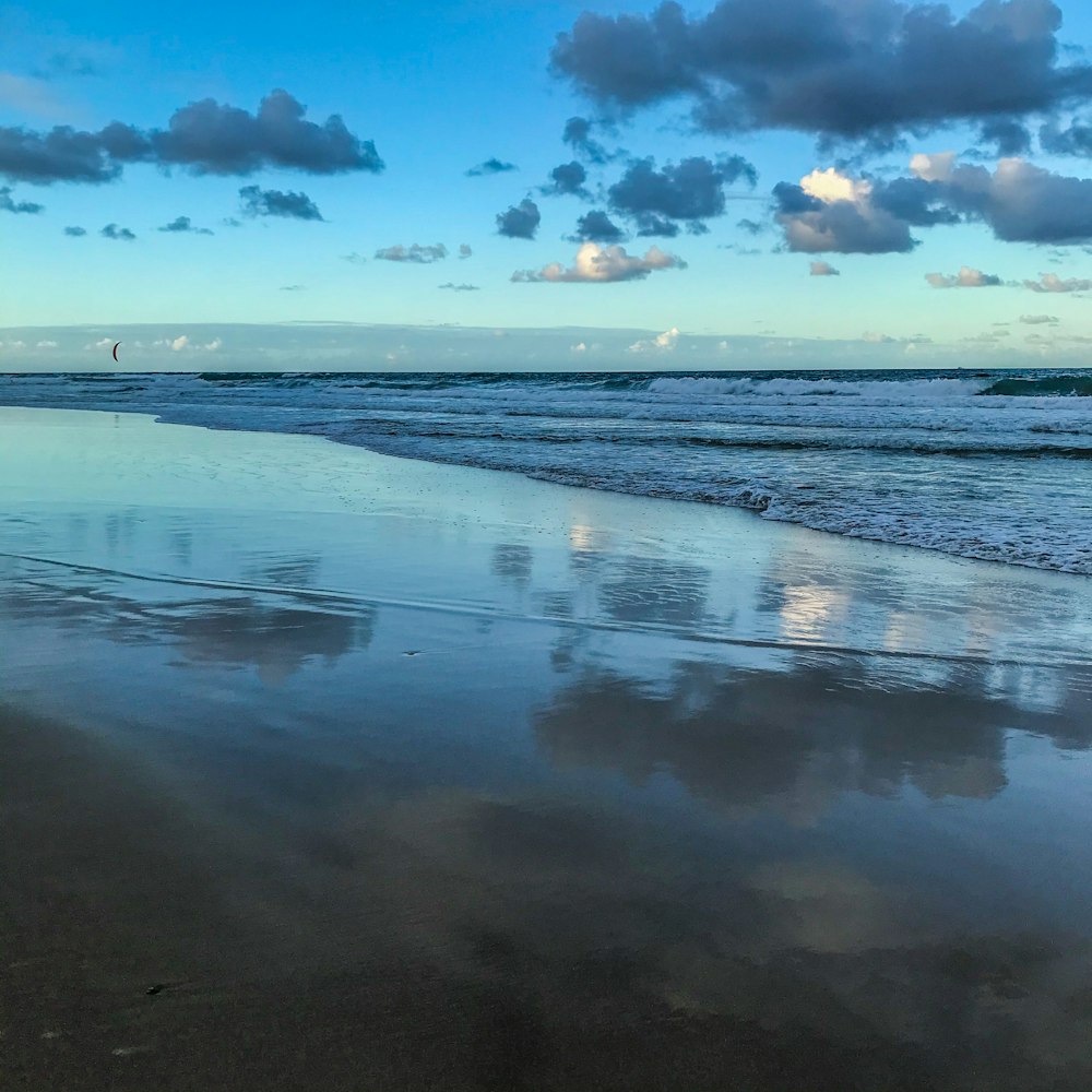 sea waves crashing on shore under blue and white cloudy sky during daytime