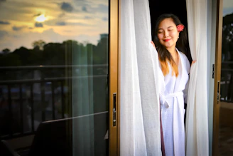 woman in white robe standing beside glass window