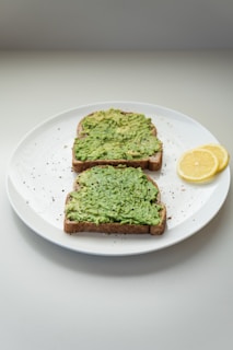 A minimalist plate with a perfectly layered avocado toast topped with microgreens and a drizzle of olive oil.