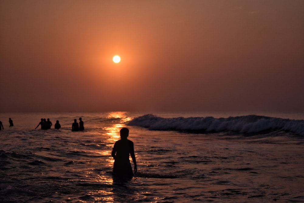 silhouette d’homme marchant sur la plage pendant le coucher du soleil