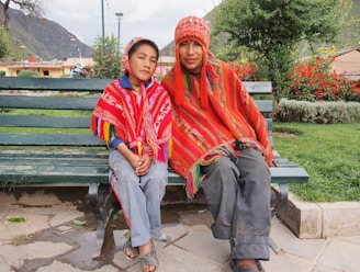 man in red and blue scarf sitting on green wooden bench