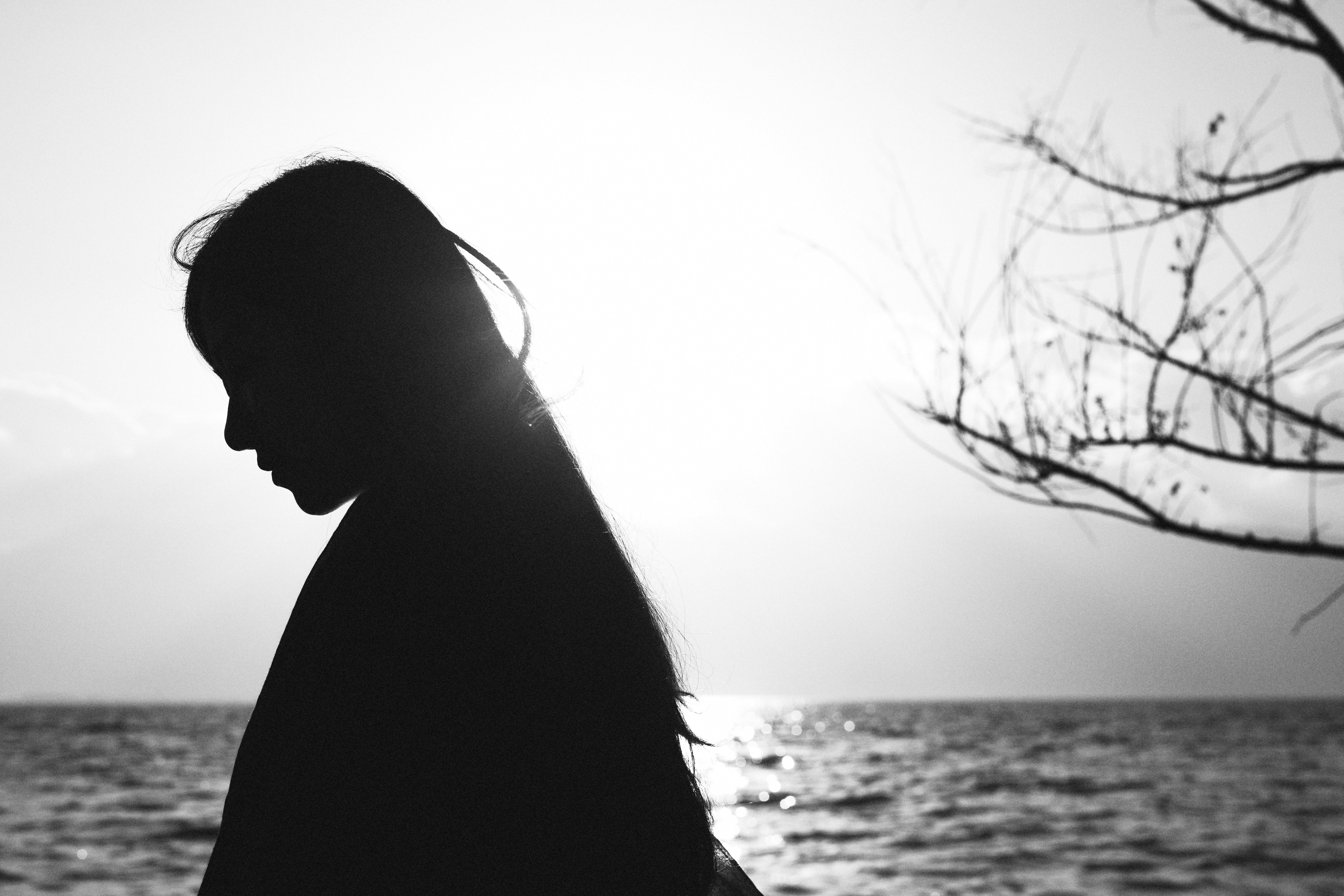 silhouette of woman standing near body of water during daytime