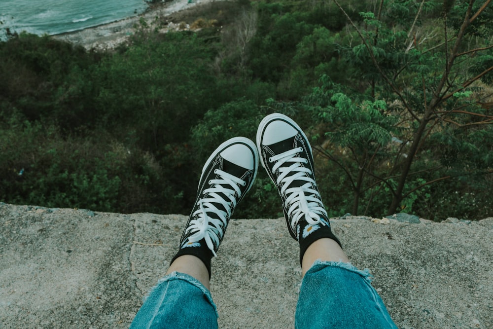 person in blue denim jeans and black and white sneakers