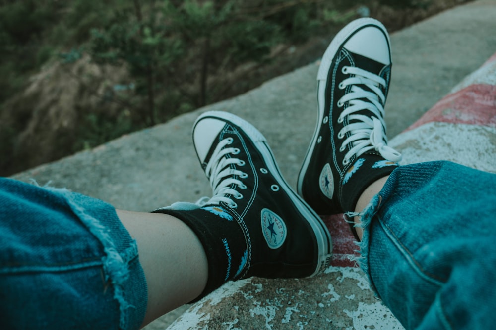 person wearing black and white converse all star high top sneakers