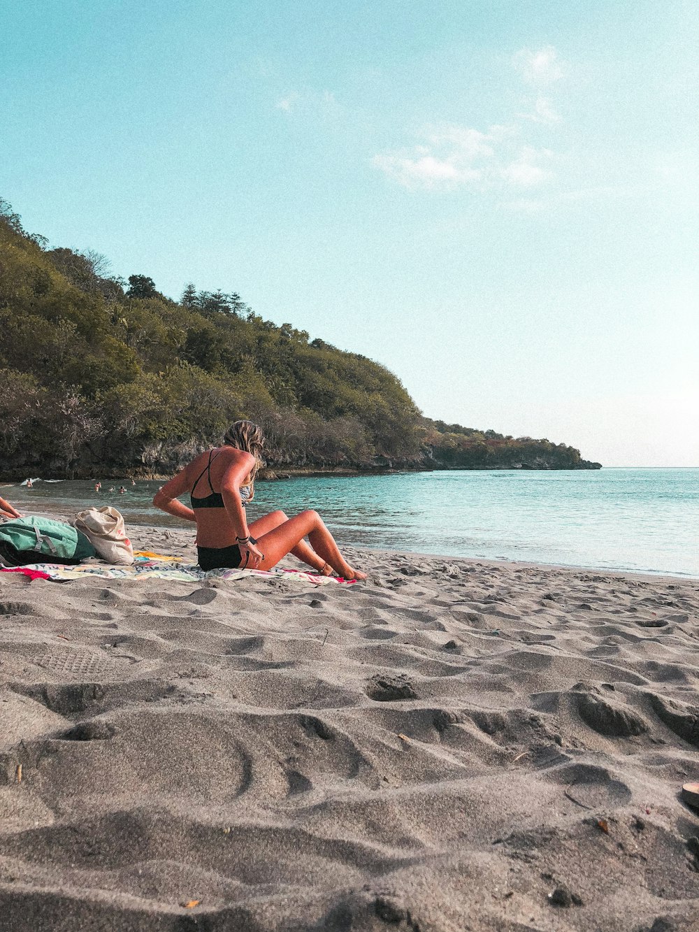 Frau im Bikini liegt tagsüber auf Strandsand