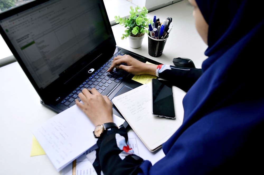 Person im blauen Langarmhemd mit schwarzem Laptop