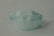 A single disposable surgical mask with pleats is positioned against a plain background. The mask features adjustable ear loops and a blue color.