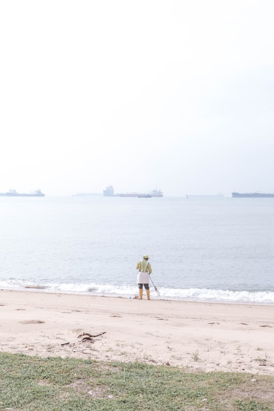 man in yellow shirt and brown shorts standing on beach during daytime in East Coast Parkway Singapore