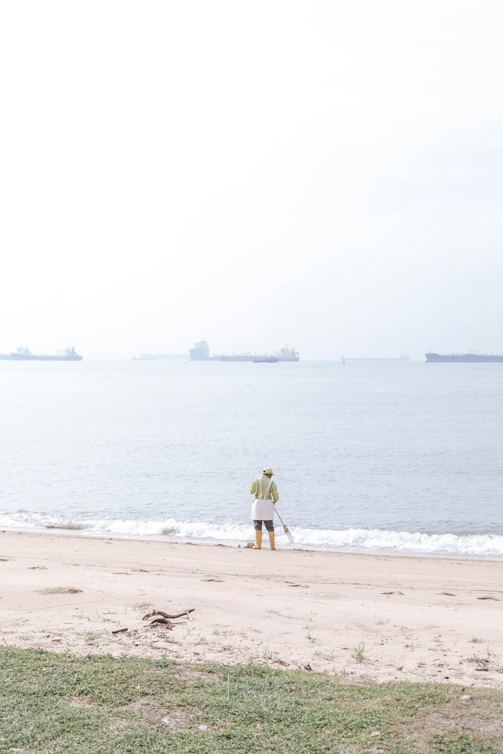 man in yellow shirt and brown shorts standing on beach during daytime