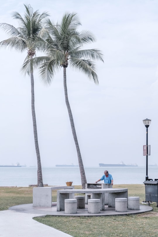 2 people sitting on boat on sea shore during daytime in East Coast Parkway Singapore