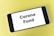 A smartphone displaying the text 'Corona Fund' on its screen is placed on a light yellow surface.
