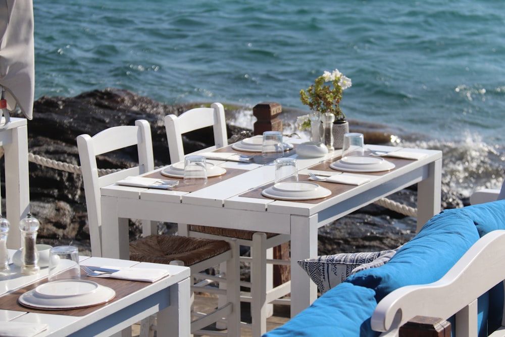 white wooden table with chairs near body of water during daytime