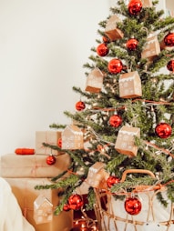 festive picture of red globe ornaments and ginger bread house ornaments on green chistmas pine tree