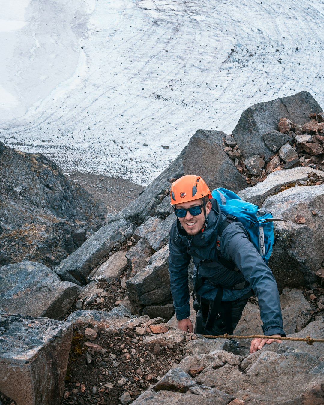 man in black jacket and orange helmet standing on rocky mountain during daytime