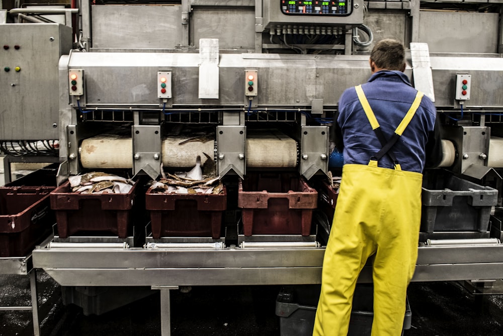 uomo in pantaloni gialli in piedi davanti all'esposizione di cibo