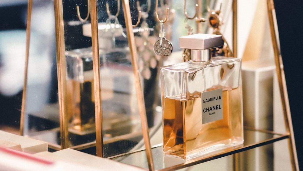 clear glass perfume bottle on glass shelf