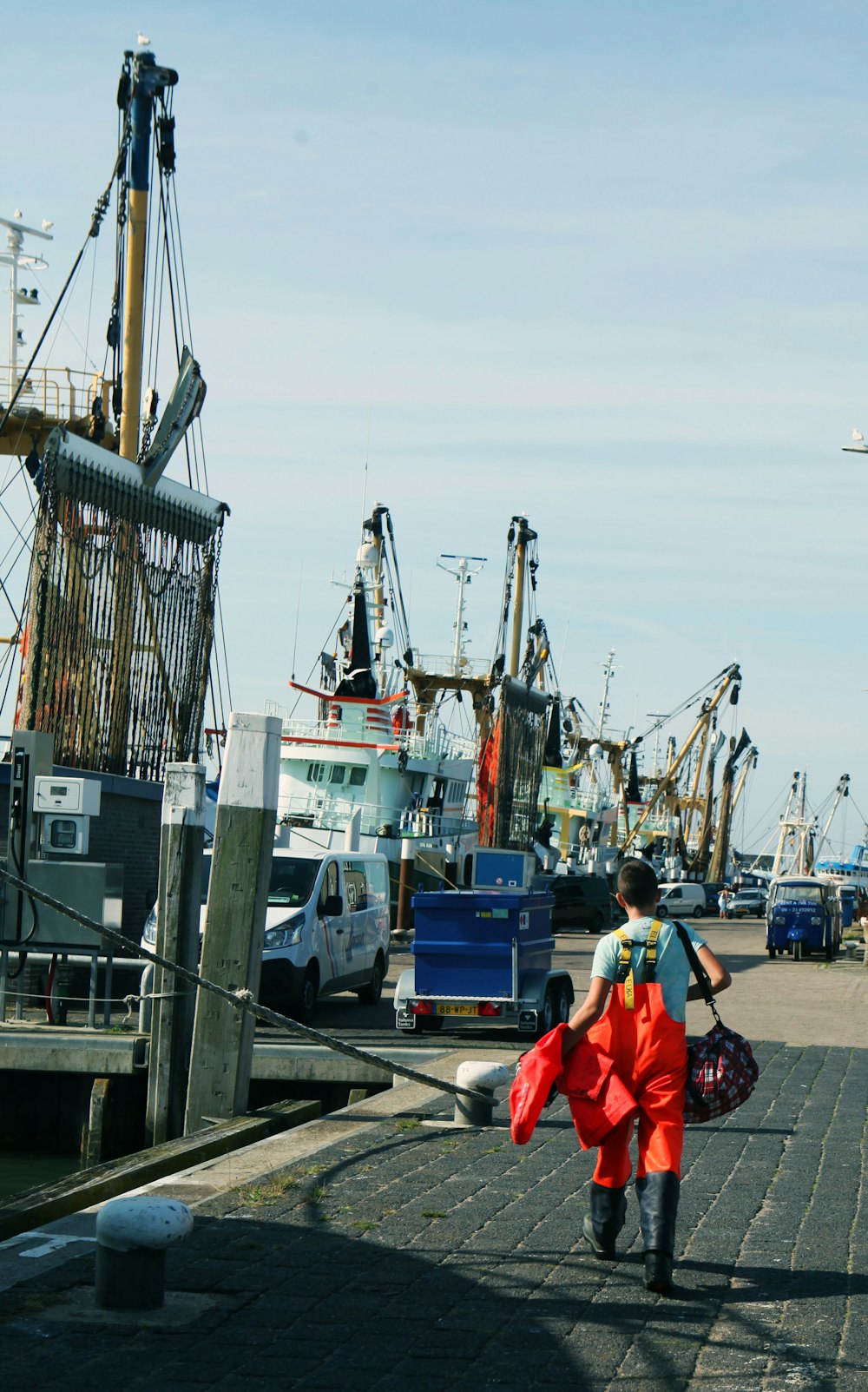 homme en veste rouge et jean bleu assis sur un bateau bleu et blanc pendant la journée