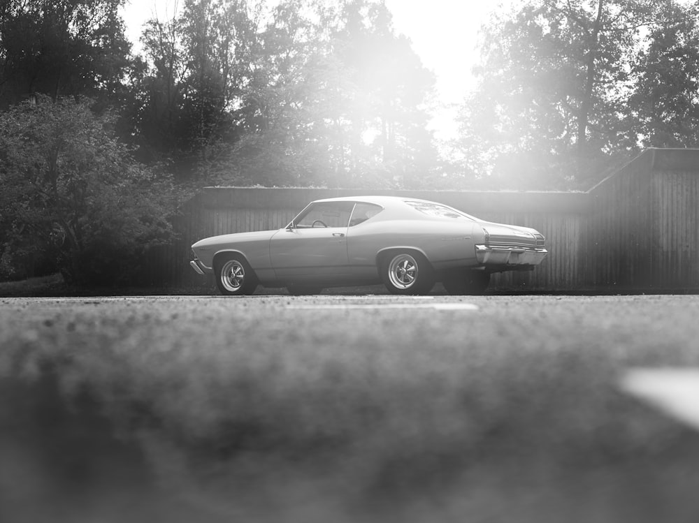 Foto in scala di grigi di una coupé su strada