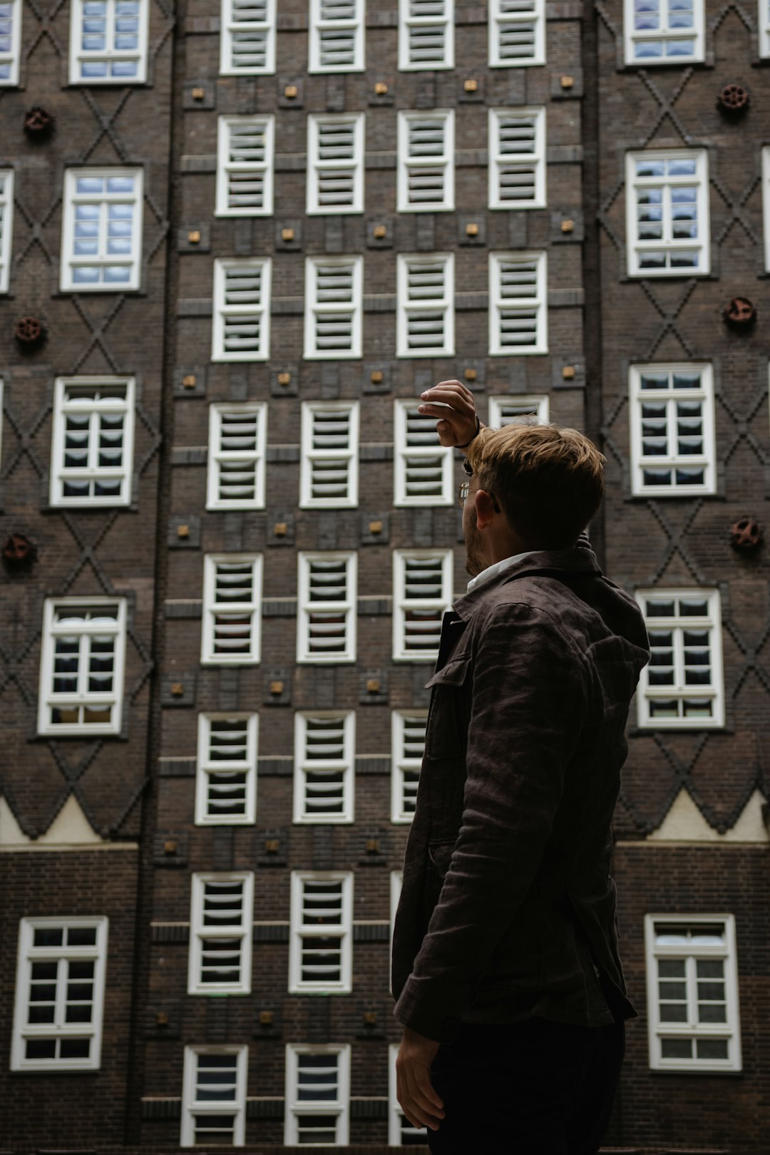 woman in black jacket standing in front of brown concrete building during daytime