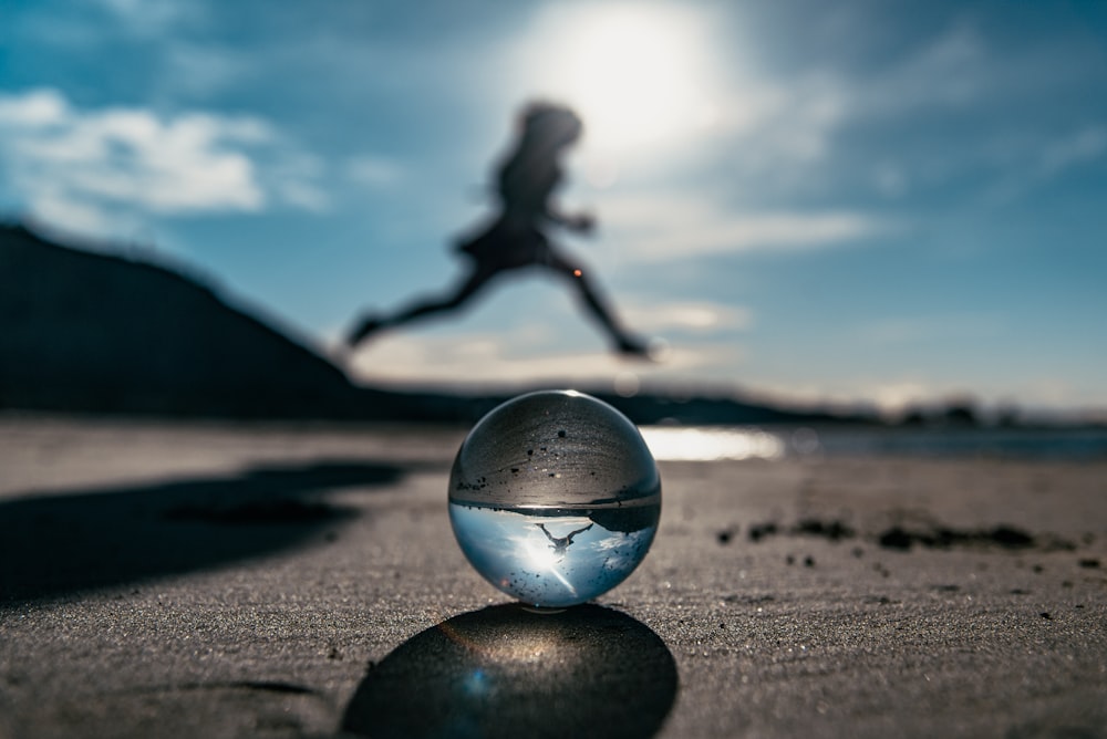 clear glass ball on brown sand during daytime