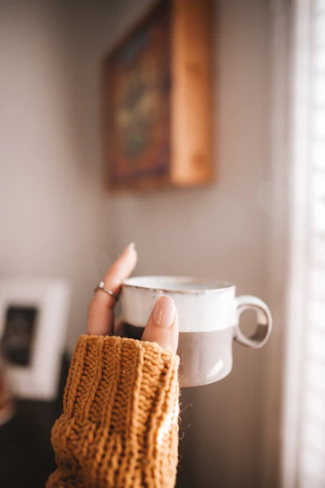 A bright, hand-thrown stoneware mug in cheerful yellow with a cozy knitted background.