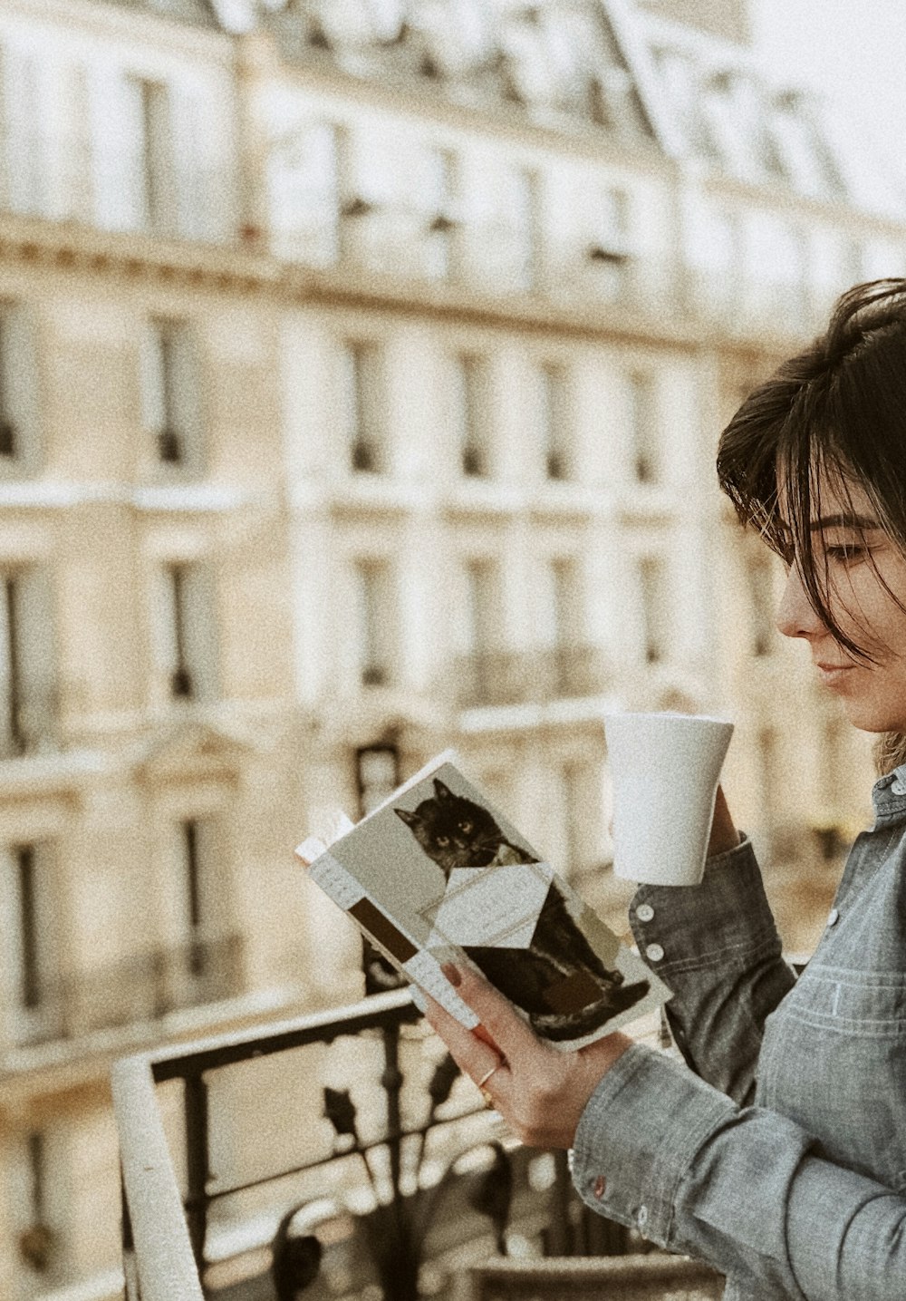 woman in blue denim jacket holding white ceramic mug