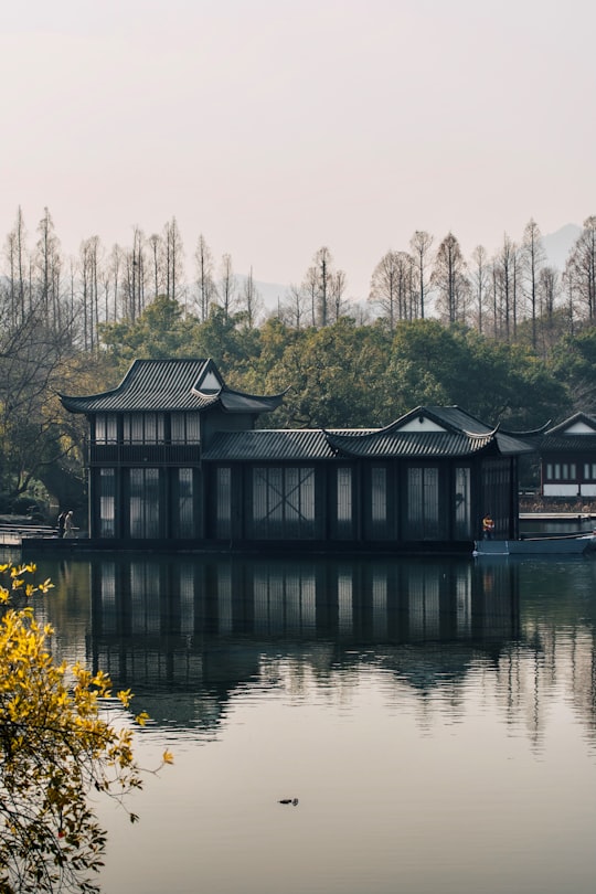 brown and white house near body of water during daytime in Hangzhou China