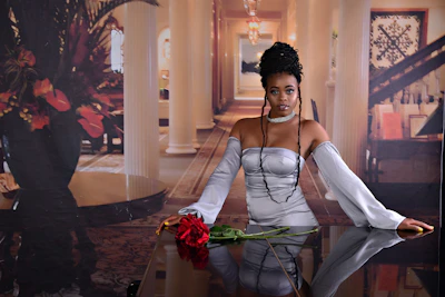 Woman wearing a sleek, modern gala dress in muted rose, posing in a bright, airy room.