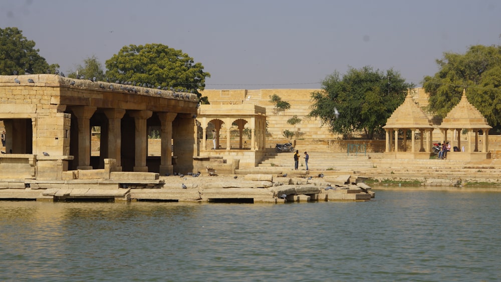 people walking on brown concrete building near body of water during daytime