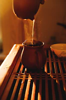 Artisan pouring golden A2 ghee into traditional clay pots under soft natural light.