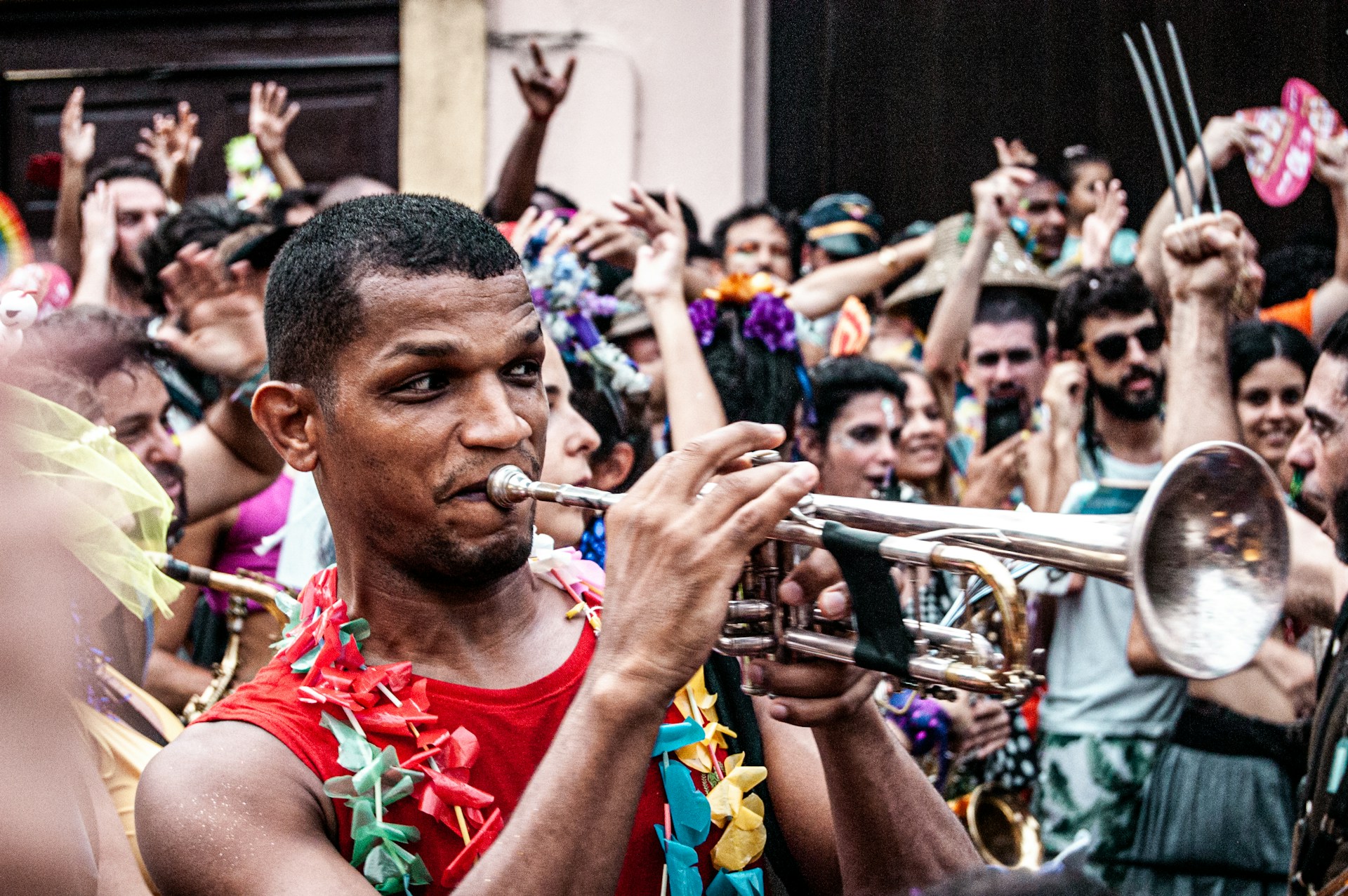 man in red tank top playing trumpet