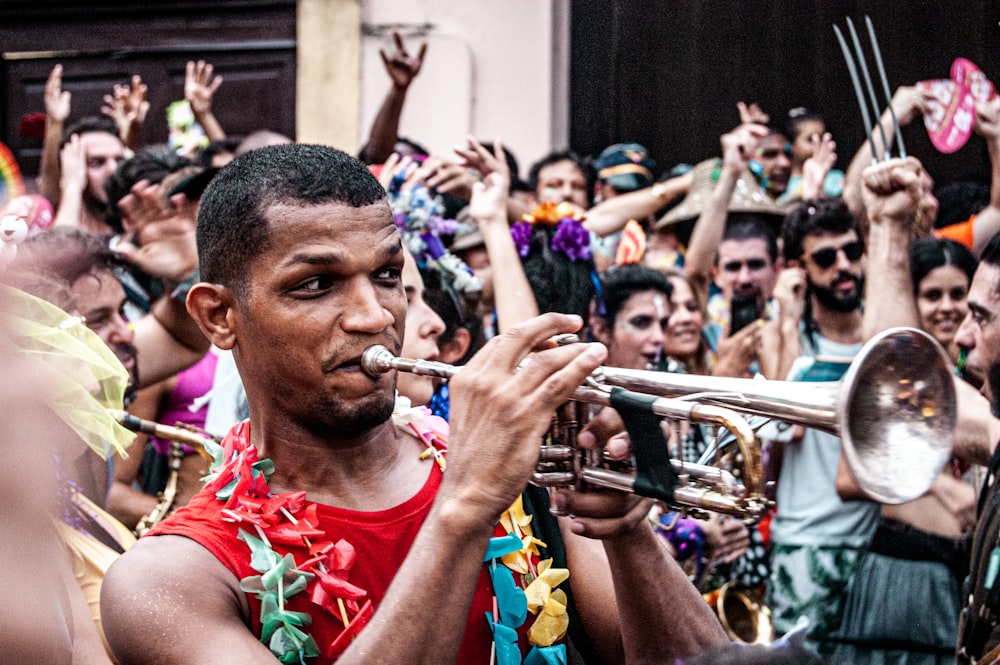 man in red tank top playing trumpet