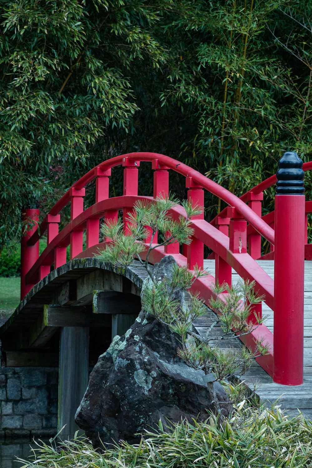 a red bridge over a small pond in a park