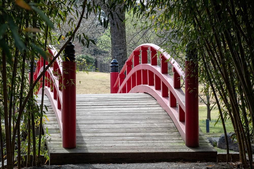 a red bridge over a small pond in a park