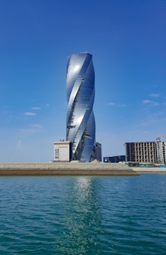 blue glass building near body of water during daytime