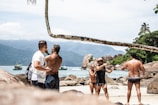 A group of friends laughing and taking photos by the sea.