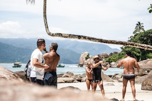 Smiling participants enjoying a weekend tour in the bright sun with the coastline of Marataízes in the background.