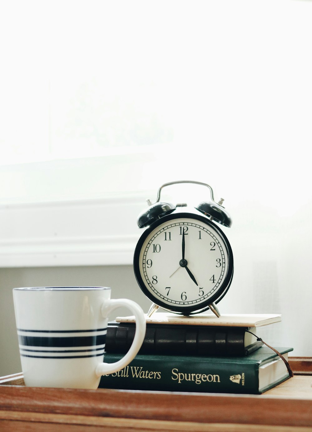 Taza de cerámica blanca junto a reloj despertador analógico blanco y negro