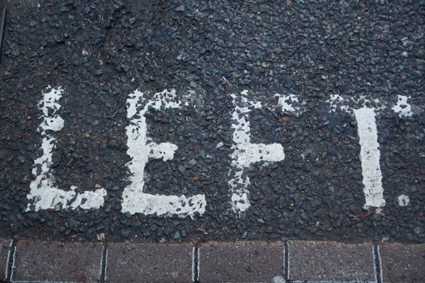 the word "left." written in fading white paint on a dark stone path