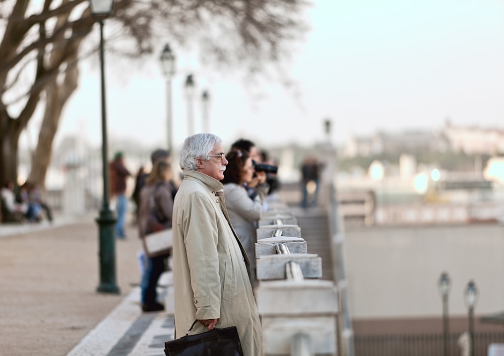 woman in beige coat walking on sidewalk during daytime