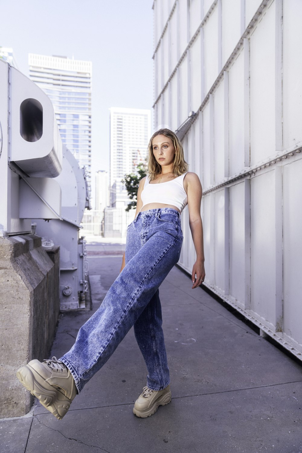 woman in blue denim jeans standing on gray concrete floor during daytime