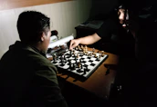 A coach guiding a student through a chess match in a modern, bright training room.