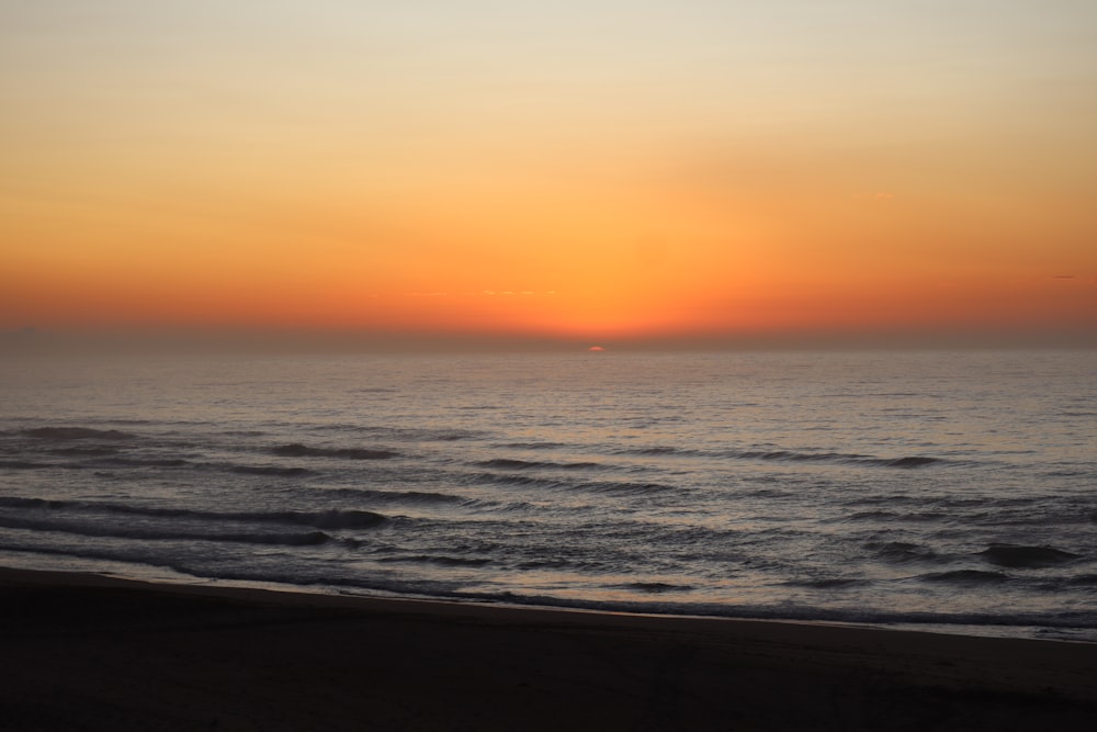 ocean waves crashing on shore during sunset